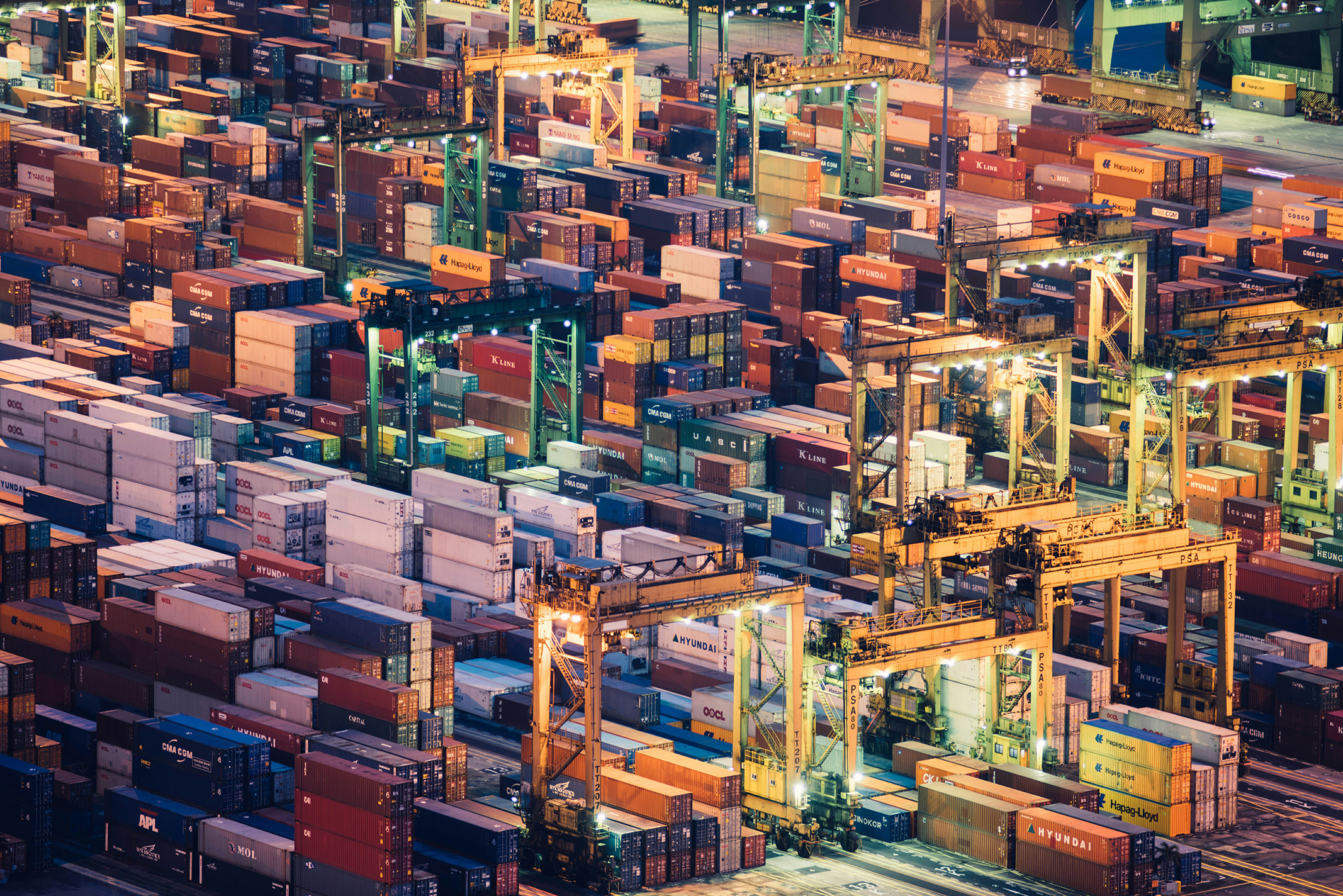 Illuminated cranes and stacked shipping containers at a working port